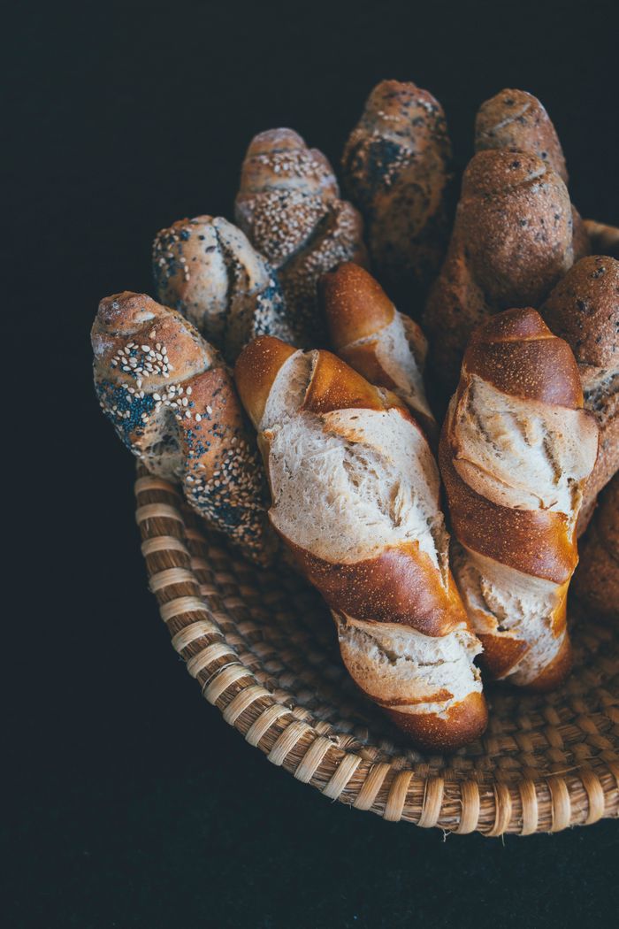 about-01 A top view of a basket filled with various freshly baked baguettes, perfect for food photography enthusiasts.