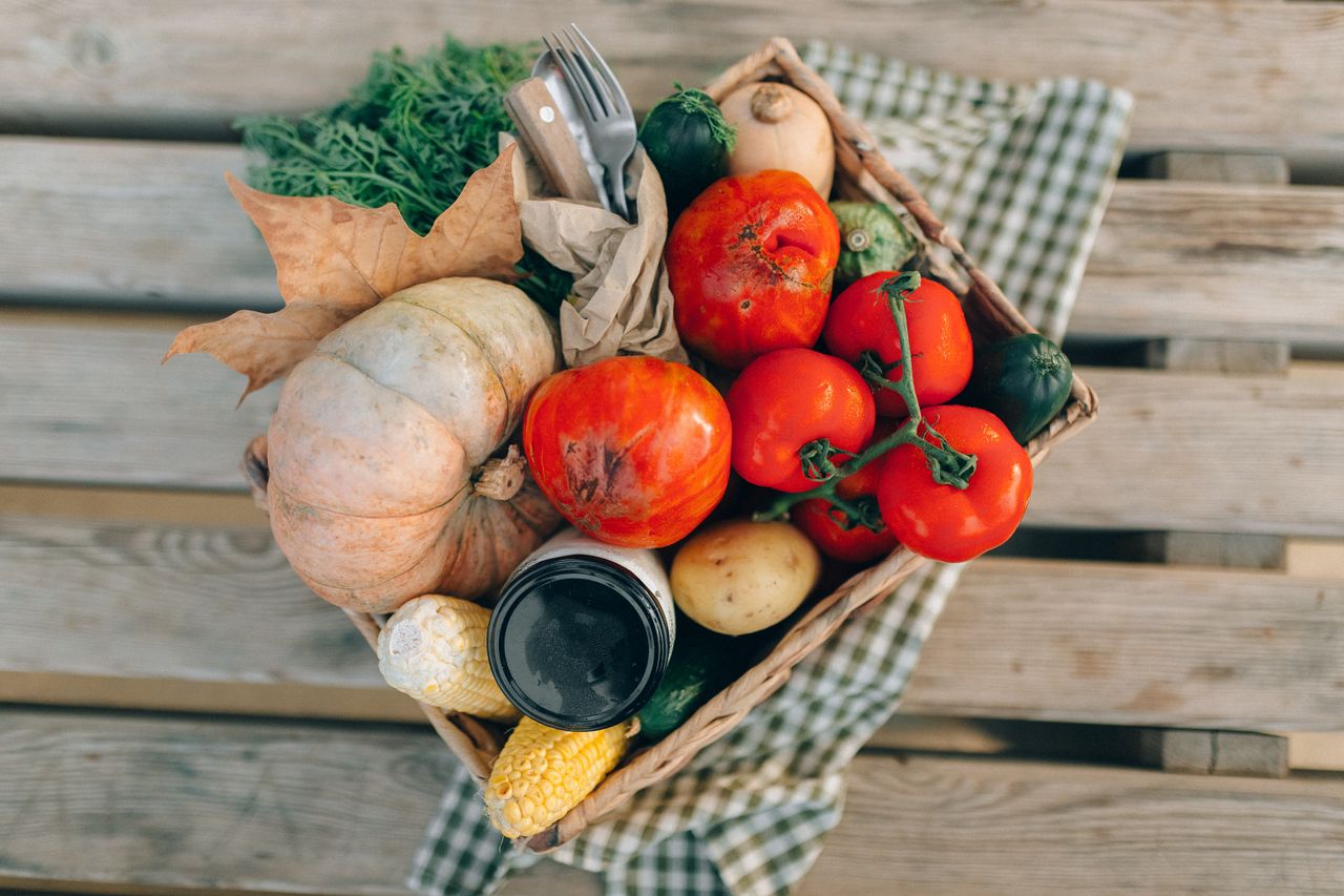 services-02 A top-down view of a basket filled with fresh vegetables and produce, placed on a wooden table.